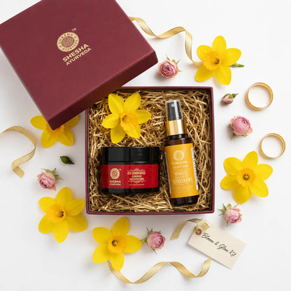 Shesha Ayurveda Bloom & Glow Kit in a burgundy gift box with Nargis flowers and gold ribbon overhead flat lay